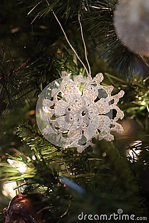 White crochet snowflake ornament hanging on Christmas tree Stock Photo