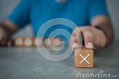 White cross mark, x, Wrong mark sign, Man showing a rejection sign in wooden cube Stock Photo