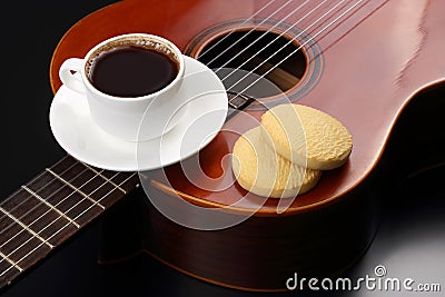 White cup with black coffee and cookies lying on the acoustic gu Stock Photo