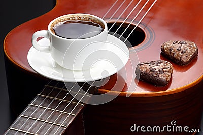 White cup with black coffee and cookies lying on the acoustic guitar Stock Photo