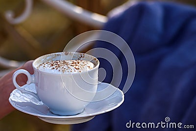 White cup with Cappuccino with cinnamon at hands. Stock Photo