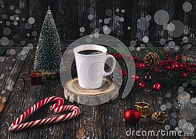 A white cup of coffee and red Christmas lollipops in the shape of a heart on a table on a dark background. Stock Photo