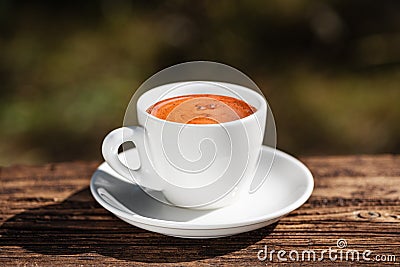 White cup of coffee on wooden table on blurred background. Beautiful golden foam. Coffee time. Copy space Stock Photo