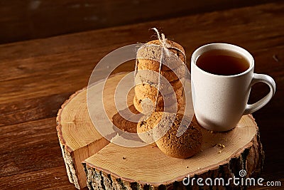 White cup of tea and bunch of cookies on a log over country style wooden background, close-up, selective focus Stock Photo