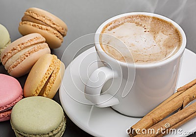 Coffee for breakfast. Multicolored macaroons, hot cappuccino, cinnamon tubes. Stock Photo