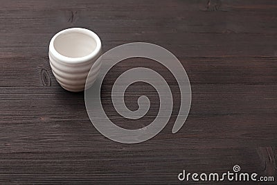 White cup for sake on dark brown wooden board Stock Photo