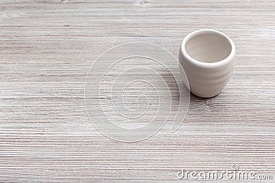 White cup for sake on gray brown wooden board Stock Photo