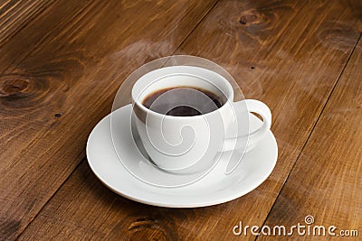 White cup of steamy coffee on wooden table Stock Photo