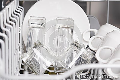 White cups, saucers and glasses in the dishwasher. front view, close up Stock Photo