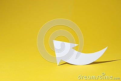 White curved paper arrow on yellow background, space for text Stock Photo
