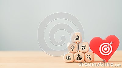 white dartboard icon on red heart and pyramid of business icon cubes on wood, brainstorming, target and goal of business Stock Photo