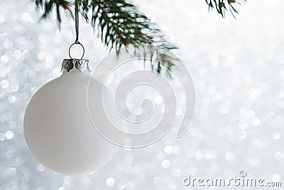 White decorative ball on the xmas tree on glitter bokeh background. Merry christmas card. Stock Photo