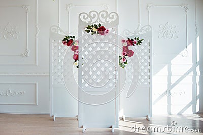 White delicate decorative wood panel in classical interior. Boudoir wedding room. Retro folding screen with flowers Stock Photo