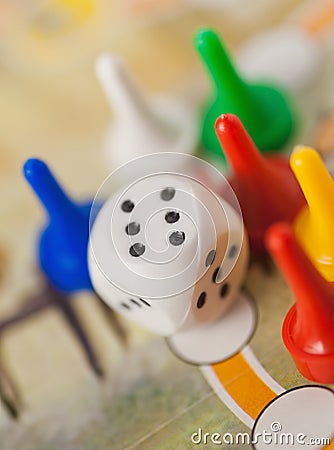 White dice cube near multicolored counter on game field Stock Photo