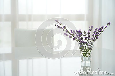 A white dining table with a bouquet of lavender and white chair are in the living room in the house Stock Photo