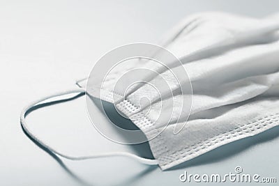 White disposable medical face mask on gray background. Single used doctor mask on table Stock Photo