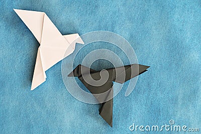 White dove and black raven paper origami in blue background. Good and evil, face fear and opposite attraction concept. Stock Photo