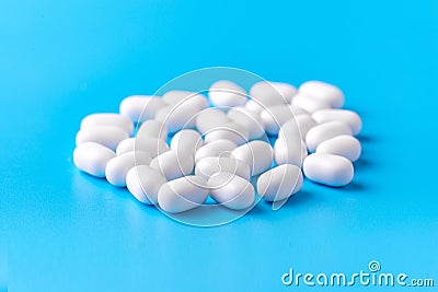 White dragees lie in a pile on a blue background. Close-up, macro photography. Lots of white mints Stock Photo