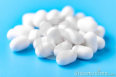 White dragees lie in a pile on a blue background. Close-up, macro photography. Lots of white mints Stock Photo
