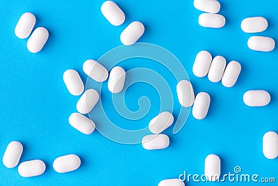 White dragees lie in a pile on a blue background. Close-up, macro photography. Lots of white mints Stock Photo