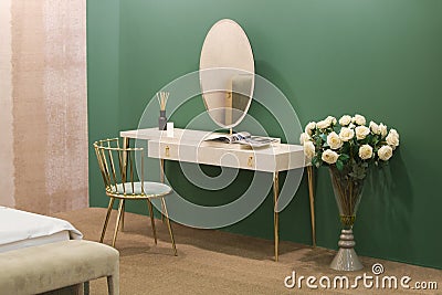 White dressing table with wicker elements, a room with a green wall and golden brass furniture, luxury mirror, female boudoir Stock Photo