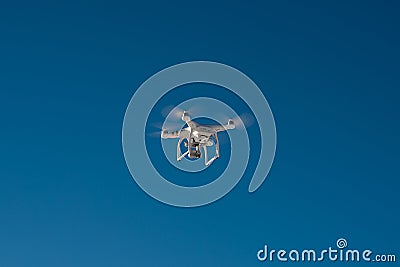 White drone quad copter with flying in the blue sky Stock Photo
