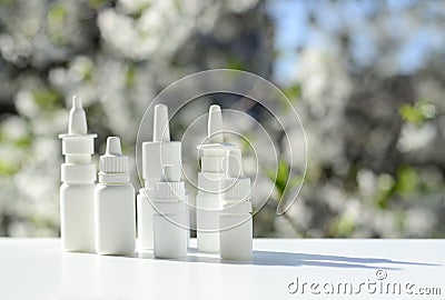 White dropper bottles, nose spray on background of spring flowering trees with copy space. Concept of allergy treatment. Nose Stock Photo