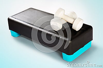 White dumbbells lie on a black-turquoise aerobic step. Stock Photo