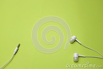 White ear buds or earphones on a green background Stock Photo