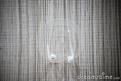 White earphone hanging on the wooden table Stock Photo