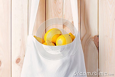 White eco bag full of lemons hang on wood wall close-up Stock Photo