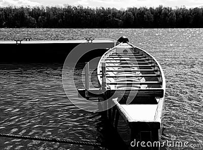 eight scull racing canoe in monochrome. anchored to a dock along a river shore. Stock Photo
