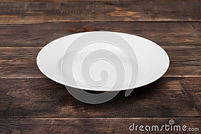 White empty plate on dark wooden table Stock Photo