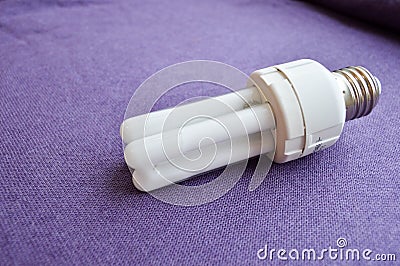 White energy-saving fluorescent light bulb with four tubes, with a silver cap Stock Photo