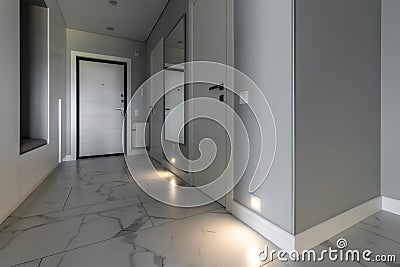 White entrance door inside the apartment in a modern interior. LED backlighting in the wall Stock Photo