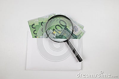 White envelope with a bunch of euro banknotes and a magnifier Stock Photo
