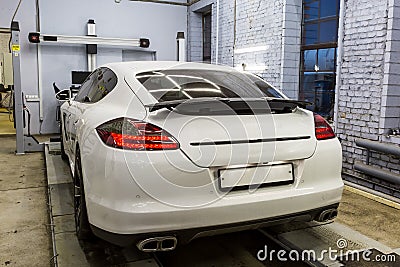 A white executive sedan stands on the stand for the gathering of the collapse. Diagnosis of the suspension and chassis in service Editorial Stock Photo