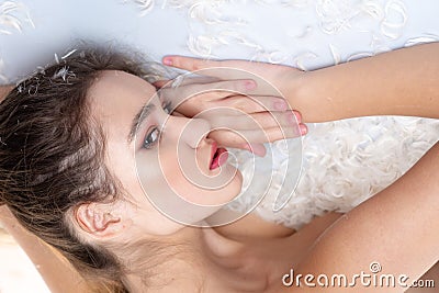 White feather soft feelings. Fashion girl makeup face relax feather bed. Skin care. Pure beauty. Pretty girl naked body Stock Photo