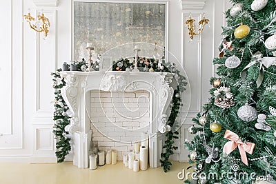 White fireplace decorated with candles and fir branches. Decorated Christmas tree. Classic apartments, morning in hotel Stock Photo