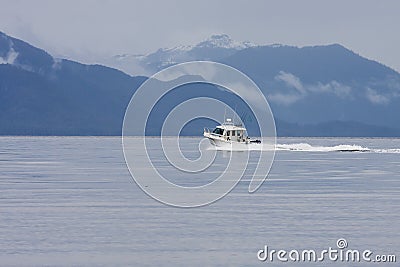 White Fishing Boat Toward Blue Mountains Stock Photo