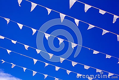 White flags waving on wind, blue sky background close up, banners flap on breeze, decorative garlands floats in air, beautiful Stock Photo