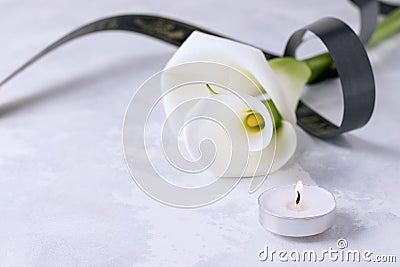 White flowers with a mourning ribbon on a concrete background. Death concept Stock Photo