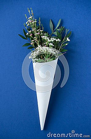 White flowers in paus tracing paper cone on blue background Stock Photo