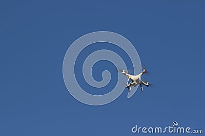 White flying drone with camera on blue sky background Stock Photo