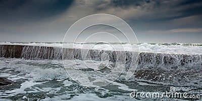 White foam waves roll through breakwater Stock Photo