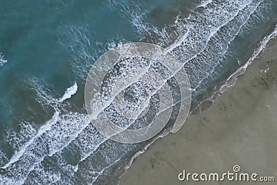 White foamy sea waves splash to deserted sandy beach in the evening. Evening surf. Aerial top view from UAV drone Stock Photo