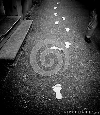 White footmark prints on a foot path showing direction and navigation to an unknown destination Stock Photo