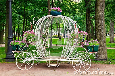 White forged decorative coach with flowers in park Stock Photo