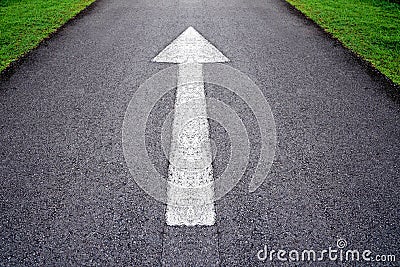 White forward arrow sign on grey asphalt road . Stock Photo