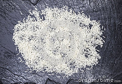White friable crude Thai rice on a stone black background. Stock Photo